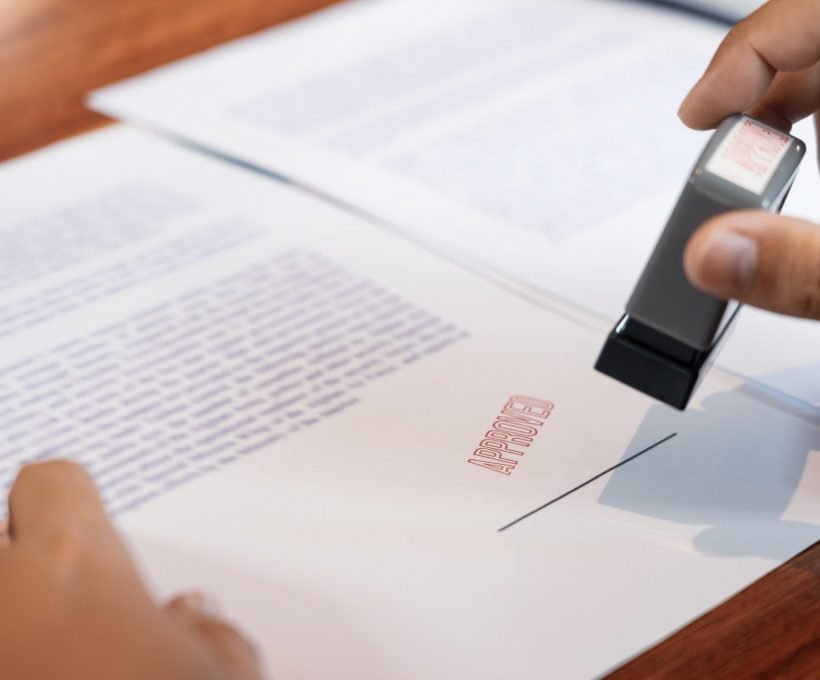 Main d'un notaire apposant un sceau sur un contrat approuvé